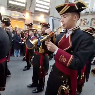 A Spanish Semana Santa marching band processing through the street during Holy Week, playing solemn brass and percussion music traditional to Easter processions in Spain." Audio description note: Loud brass instruments and drums playing a traditional procession march.