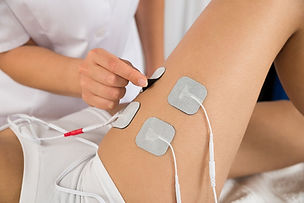 Aplicación de electrodos para electroterapia en la pierna durante tratamiento de fisioterapia