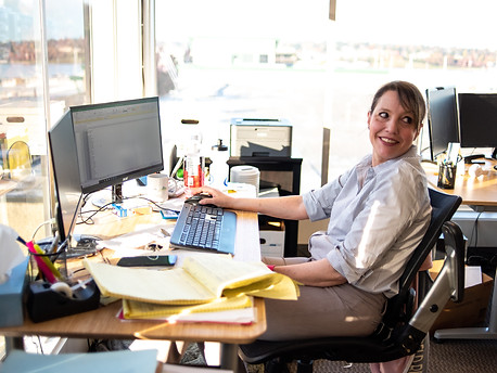 an employee looks backwards over her shoulder while sitting at her desk