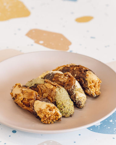 Mixed Selection of Cannolis on a pastel pink plate with the terrazzo print table in the background