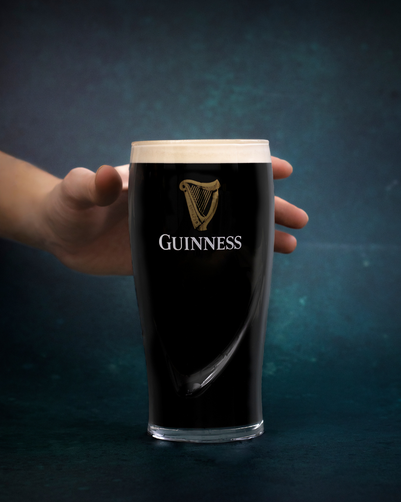 Guiness glass with a hand coming from the back to grab the glass