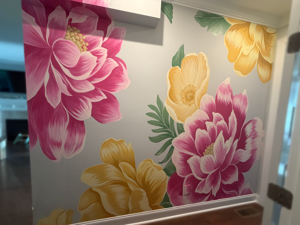 Hand-painted floral wall mural with large pink and yellow flowers on a light gray accent wall in a modern residential hallway.