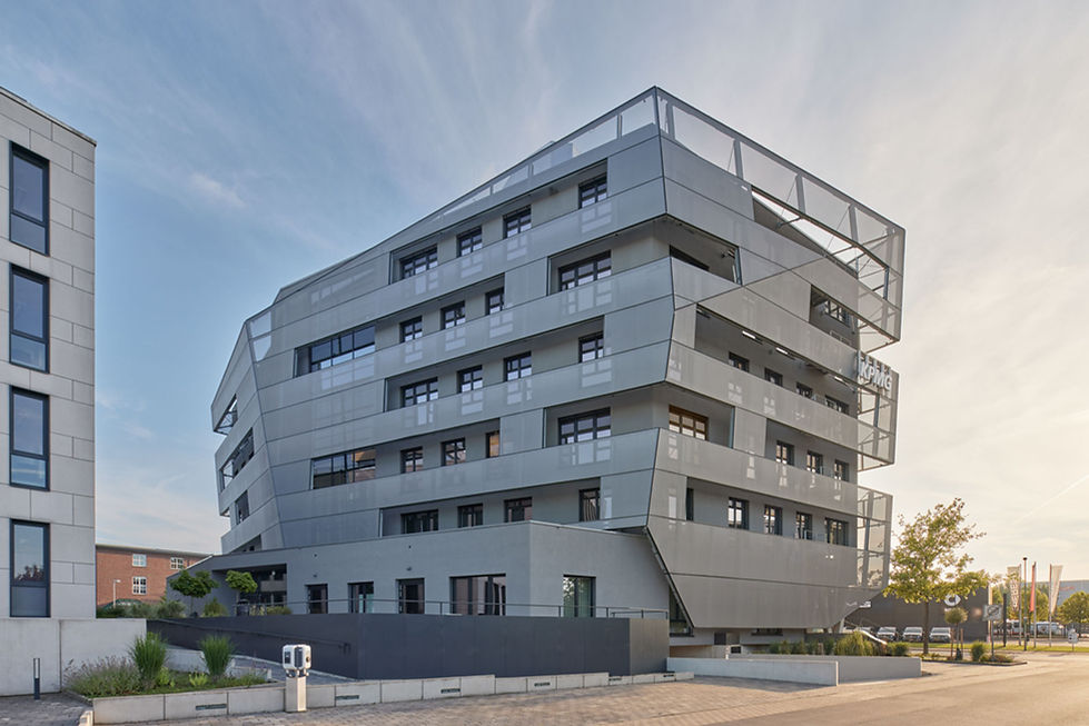 Gesamtansicht des KPMG Gebäudes am Lenkwerk in Bielefeld von der Ostseite im Gegenlicht der untergehenden Sonne. Deutlich zu sehen sind die teiltransparenten Fassadenteile aus Textilmaterial die die Asymmetrie der Gebäudefront bilden.