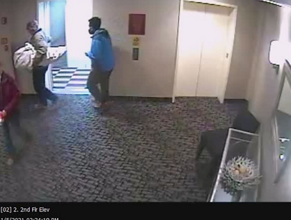 Individual concealing a rifle in hotel hallway