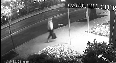Individual walks by Capitol Hill Club holding a bag