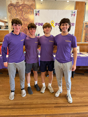 4 smiling volunteers wearing a purple Finley Forever tshirt and posing for the camera