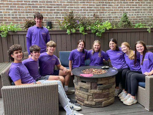 Young volunteers sitting around a round table wearing the purple Finley Forever t-shirt