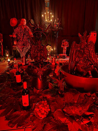 Ambiente ritualístico sombrio sob luz vermelha com altar e garrafas.