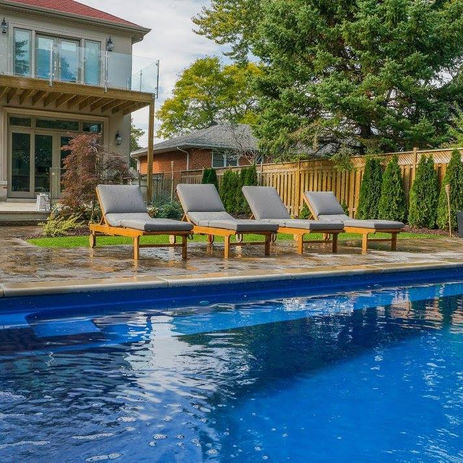 A picture of a pool with its seating in front of a house.