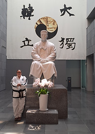 MAster Kirsten standing in front of staue of Ahn Joon Gun -Korea
