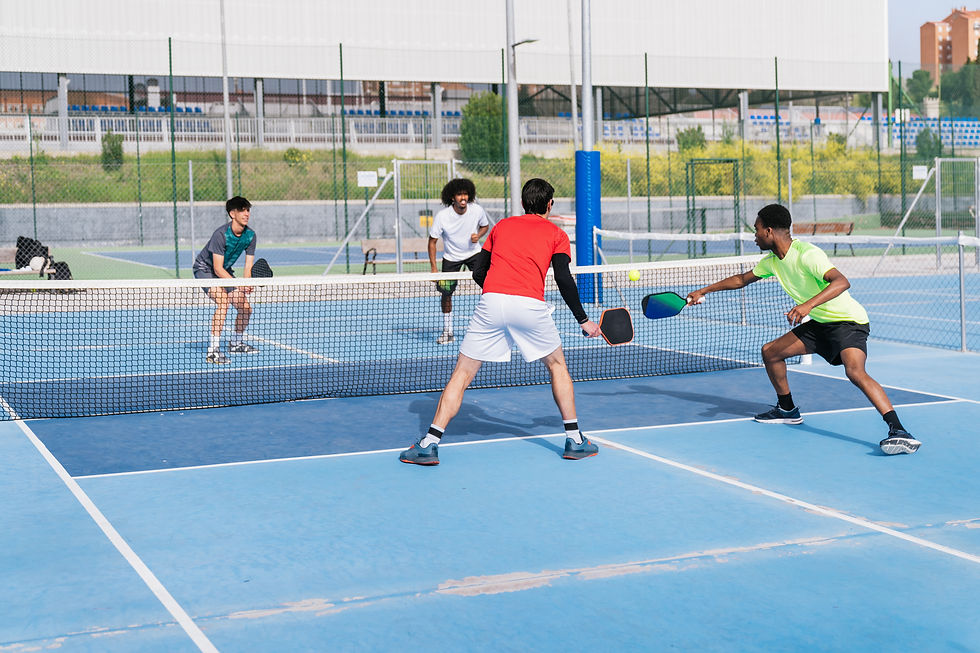 Four players engaged in a competitive pickleball doubles match, with one player preparing to return the ball, illustrating tournament preparation strategies from the blog post."