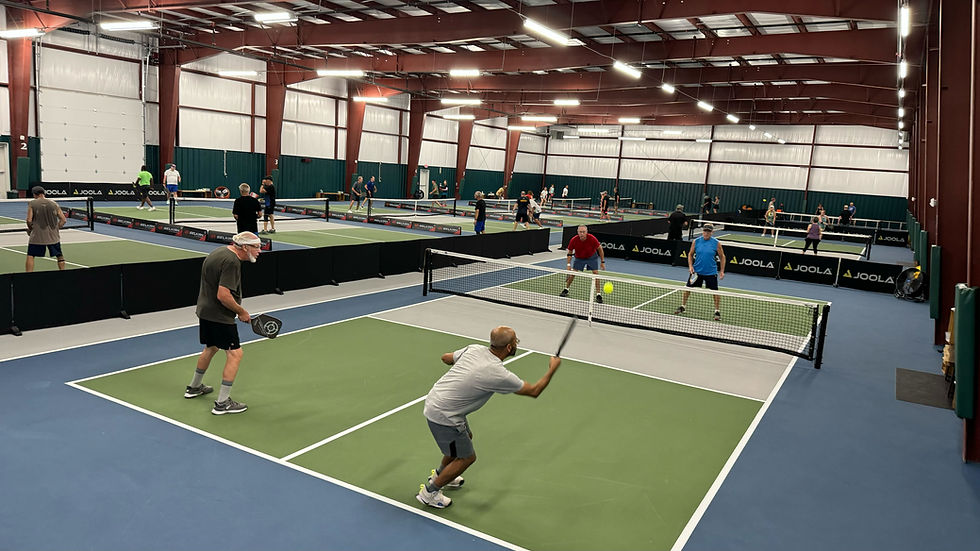 Players engaged in various games of pickleball in a spacious indoor facility with multiple courts. This image visually supports the blog post about IPC valuing senior pickleballers by showing a diverse group of players actively participating in pickleball games at an indoor facility, illustrating the club’s commitment to providing a welcoming and active environment for players of all ages, particularly seniors.