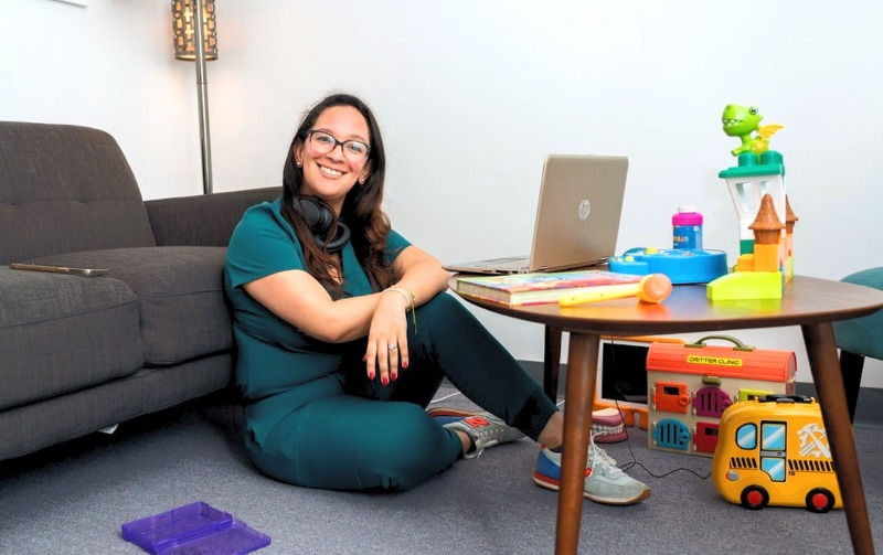 woman sitting on the floor with a laptop and toys around her