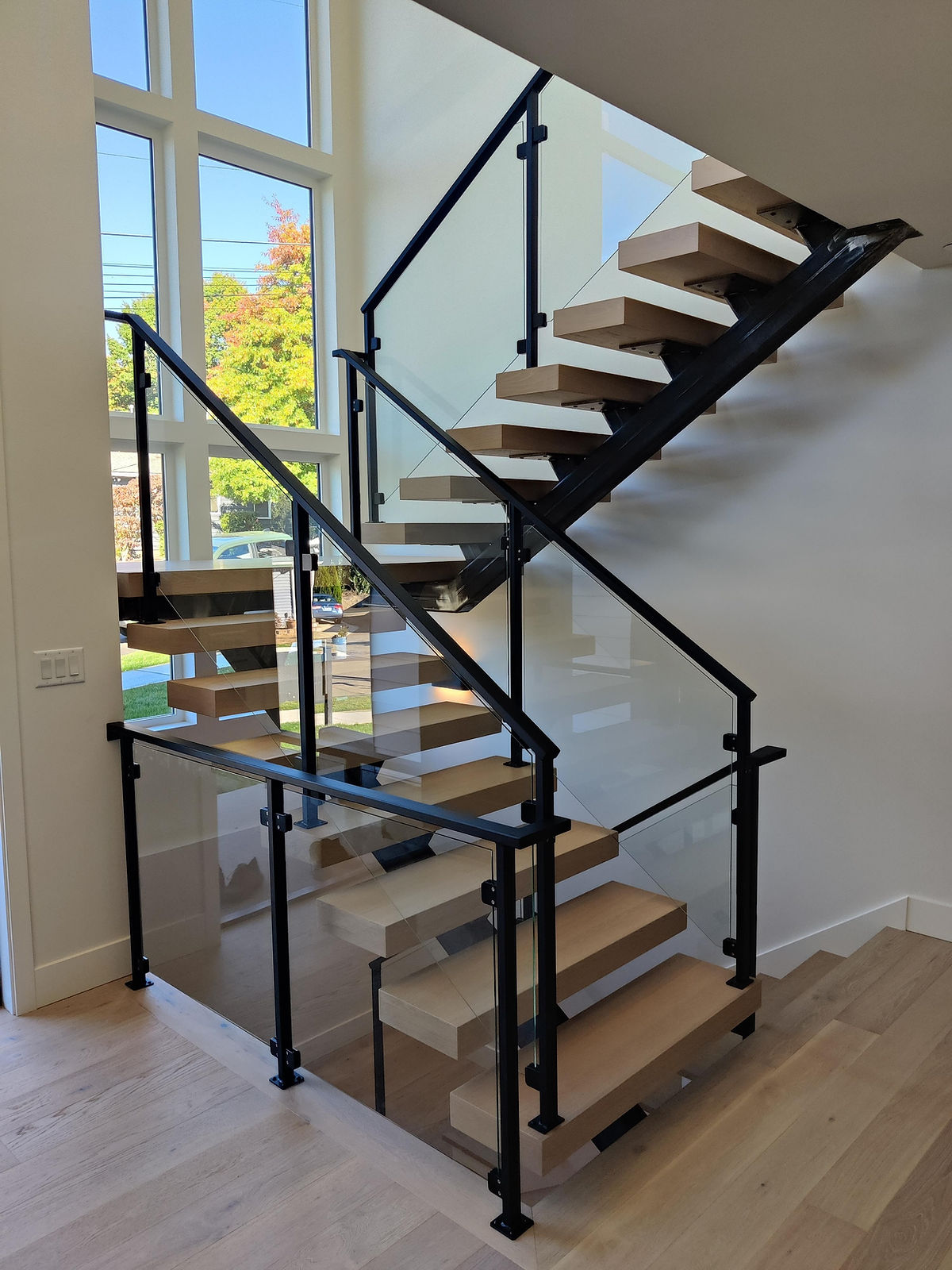 Interior single beam steel staircase with glass panel rails. — view 2