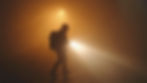 Silhouette of a person wearing a helmet, holding a flashlight in a foggy, orange-lit setting. The mood is mysterious and tense. Mars. Icarus scifi book.