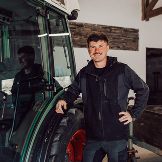 Johannes Koch steht am Traktor, der in der Scheune steht
