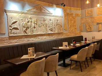 Teil des großen Saals des Restaurants Helena in Neustrelitz mit griechischen Dekorationen an den Wänden und an der Decke hängen Blumengirlanden