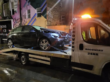 Black damaged car being towed after an accident