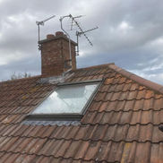 New roof tiles installed with roof window and chimney in background