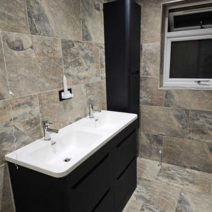 Black bathroom cabinet and white sink and marble effect tiles