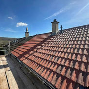New roof with dark red tiles and scaffolding around roof