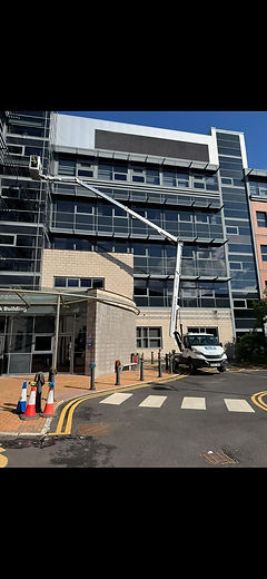 Building exterior with street and car. White van parked in front of hospital.