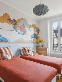 décoration intérieure, chambre enfant, papier peint panoramique, fresque murale, lits jumeaux, terracotta, bleu pastel, linge de lit, style scandinave, design poétique, aménagement petit espace, décoration murale, mobilier en bois, commode design, lampes de chevet, rideaux en lin, atmosphère douce, tendance déco 2026, chambre partagée, illustration nature, ocre, moutarde, coussins rayés.
