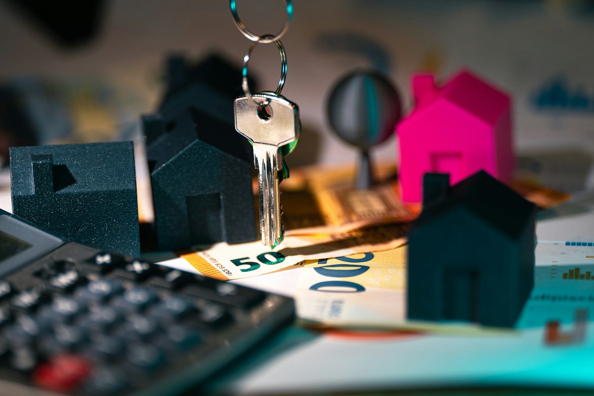 Calculator and small house model representing capital gains tax on a home sale in Lakewood, CO