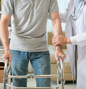 unrecognizable-female-doctor-helping-male-patient-walk-with-walking-frame.jpg