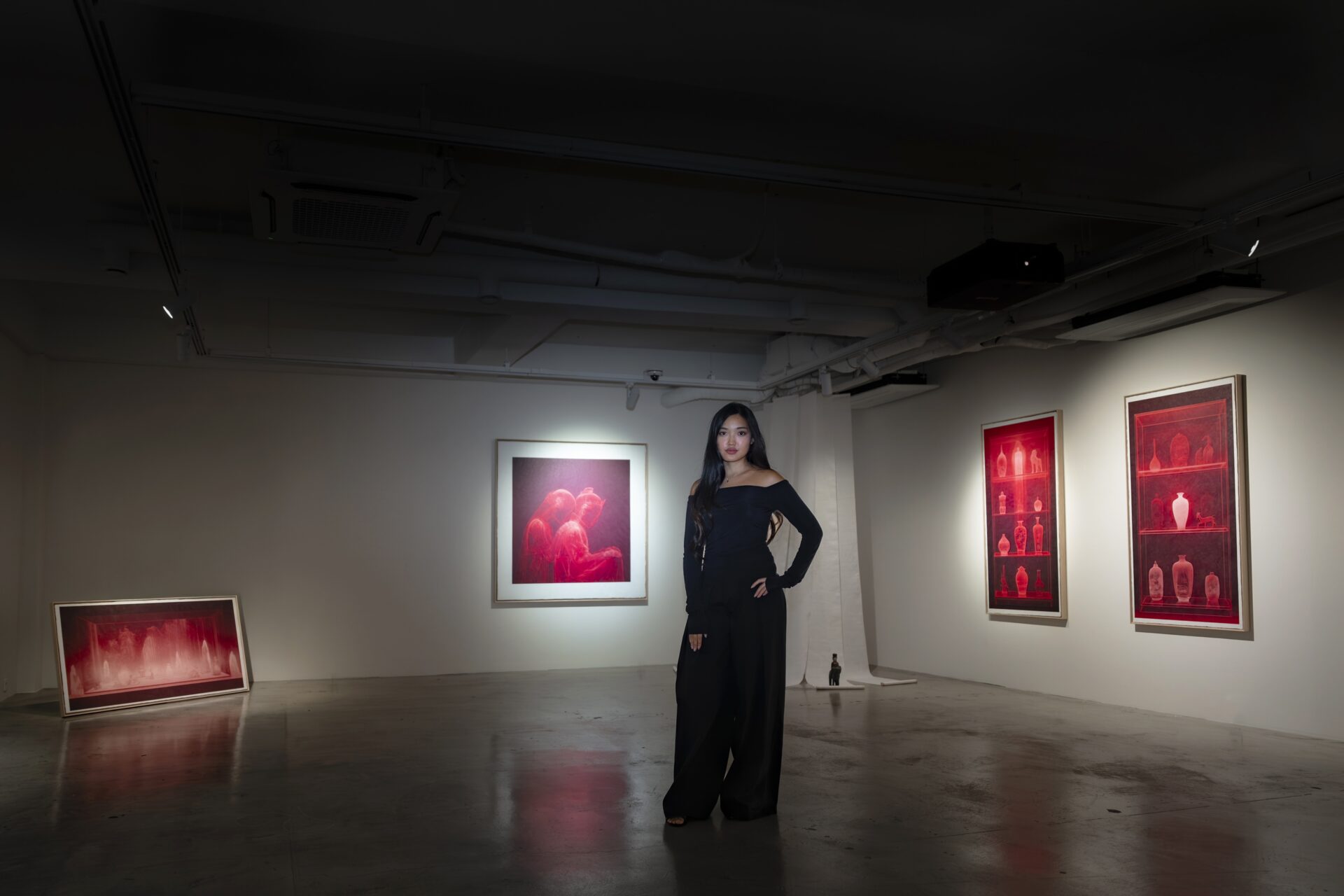 Ming Shiu dans l’exposition The Crimson Hour à Séoul, devant des œuvres rouges associées à Genesis Kai.