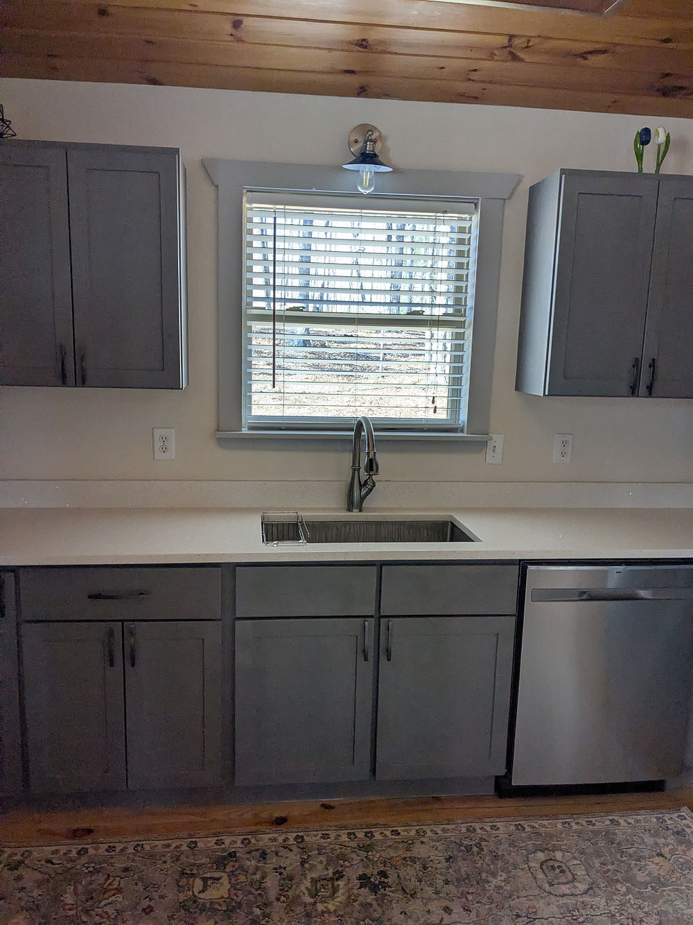 Cozy kitchen with gray cabinets and wood ceiling.