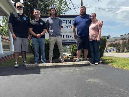 Five people standing in front of a property management company's sign