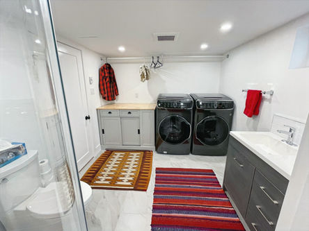 Completed bathroom with glass shower, washer, dryer and new sink.