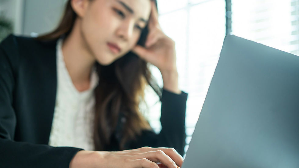 Junge Frau sitzt nachdenklich vor einem Laptop und wartet auf eine Antwort auf ihre Bewerbung, symbolisch für fehlende Rückmeldungen auf Lehrstellenbewerbungen.