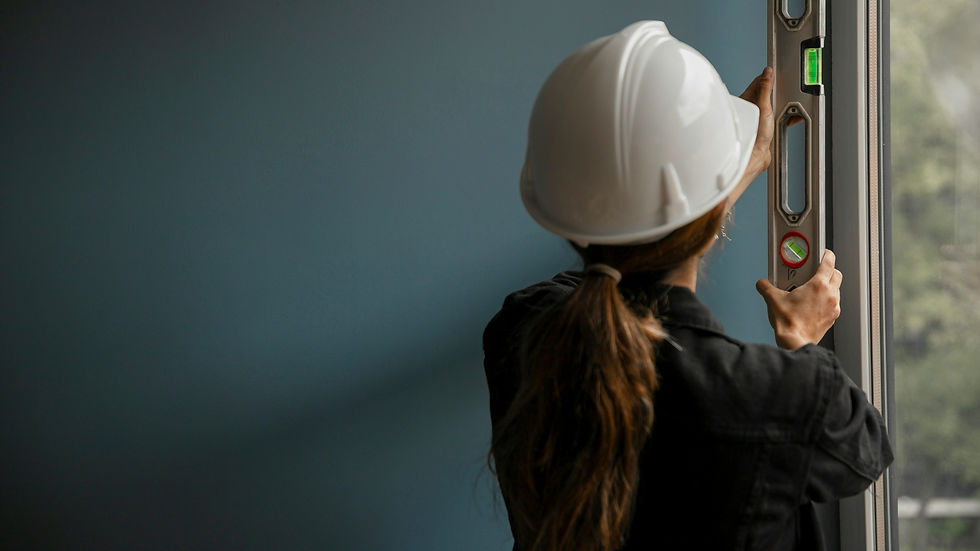 Frau mit Schutzhelm arbeitet mit einer Wasserwaage an einem Fensterrahmen auf einer Baustelle, symbolisch für Frauen in technischen und handwerklichen Berufen.