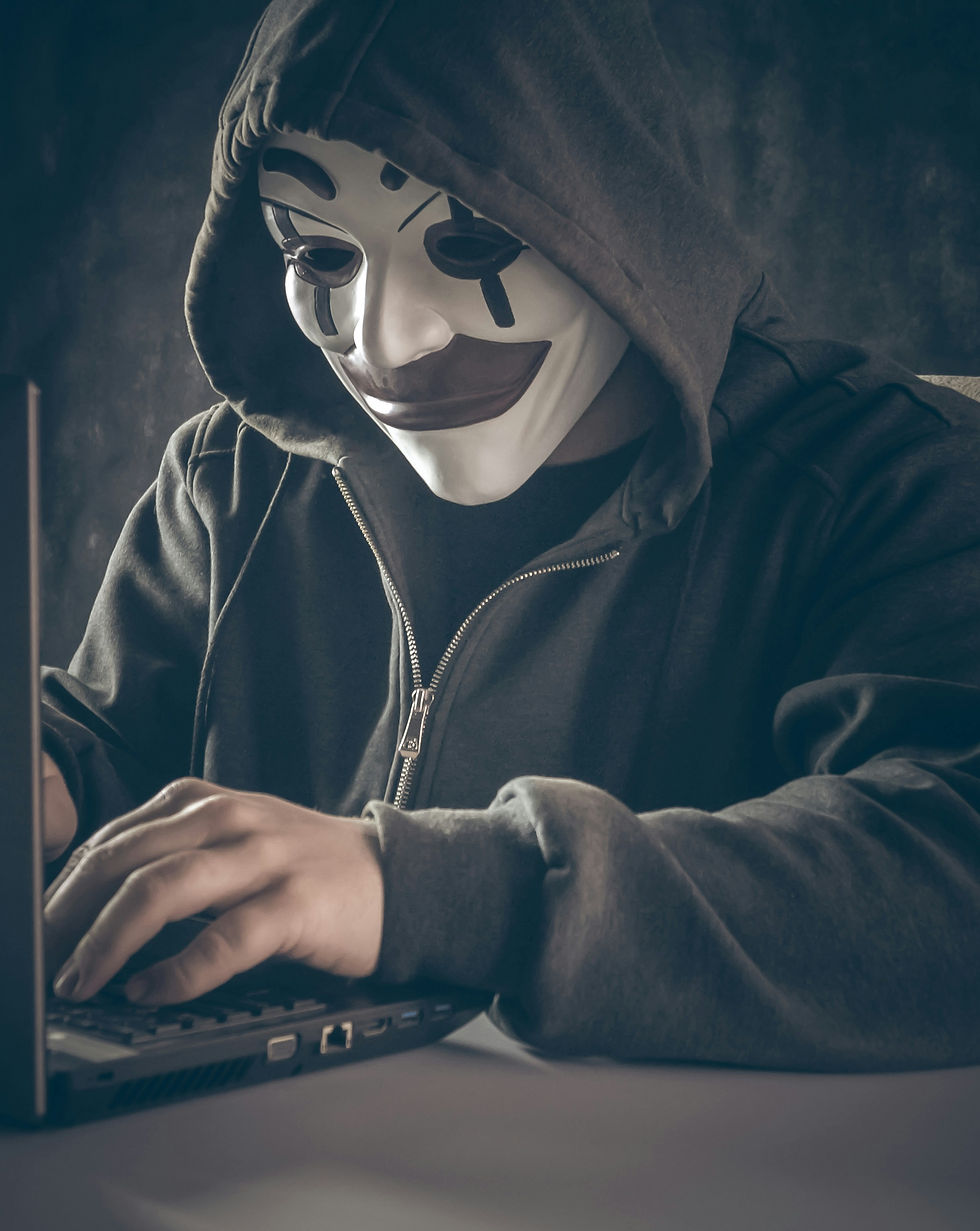 A clown-masked person in front of a computer