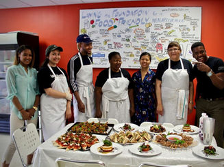 Group of 6 chefs pose behind a table holding the many dishes they prepared.