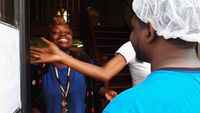 Smiling woman in due rag sticks her tongue out at friend.
