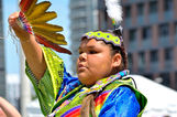 Young child dressed in traditional first nation attire performs at festival.