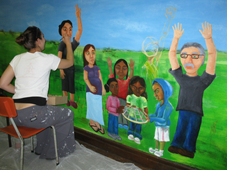 Woman in chair finishes painting a mural.