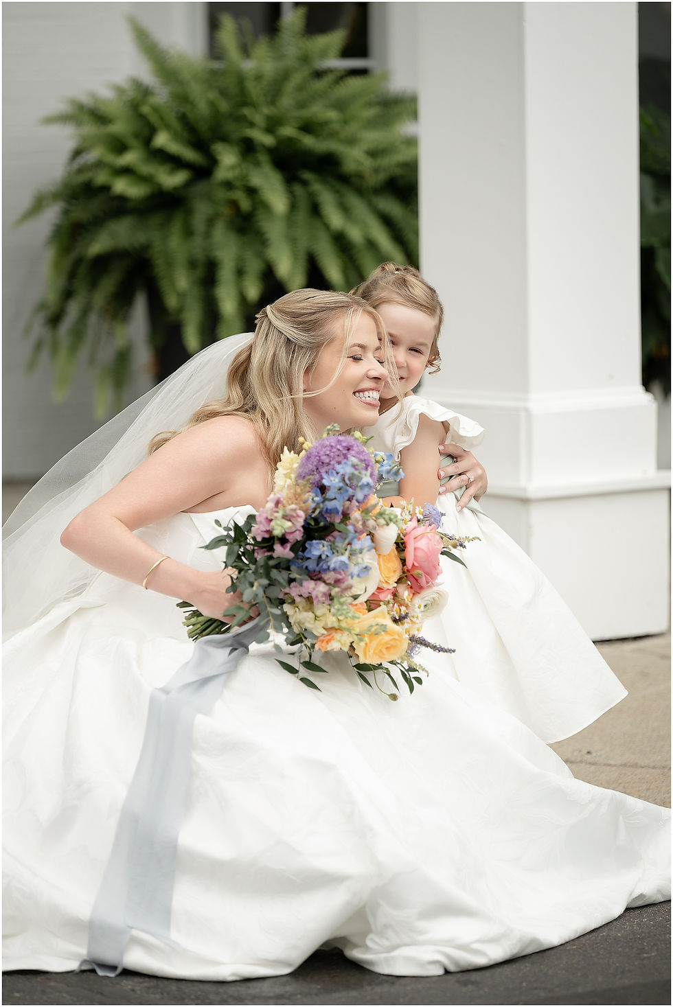 Bride hugging flower girl at black iris estate
