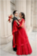 Bride in a red lehenga and groom in a black tuxedo for wedding photos at the Indianapolis Central Library