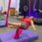 Intro to aerial silks adult student in coffin pose on pink aerial silk.