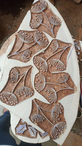 A slice of wood with wooden blocks carved on it before being cut out