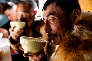 Kazakh eagle hunter drinking tea inside a family home in western Mongolia