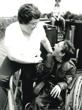 Black and white photo: woman interacting with a child in a wheelchair