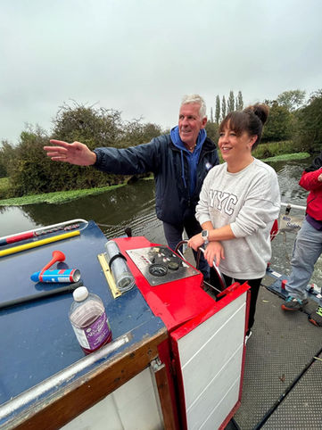 Skipper and visitor on canal boat, learning to steer the boat