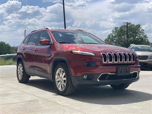 A red Jeep SUV is parked on pavement in a car lot.