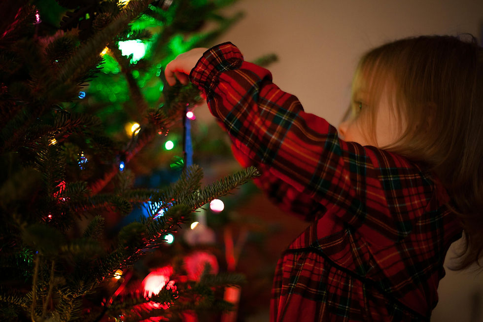 girl in pyjamas hanging decoration on a christmas tree