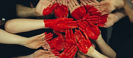 Group of hands put together with red paint to form a heart